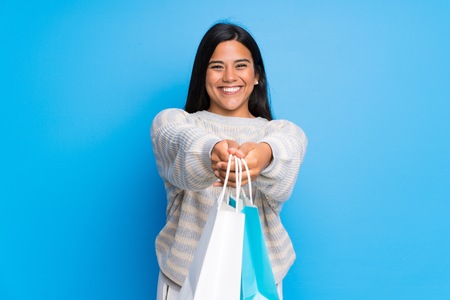 Young Colombian girl with sweater holding a lot of shopping bagsの写真素材