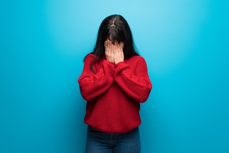 Woman with red sweater over blue wall with tired and sick expressionの写真素材