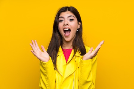 Teenager girl over yellow wall with surprise facial expressionの写真素材