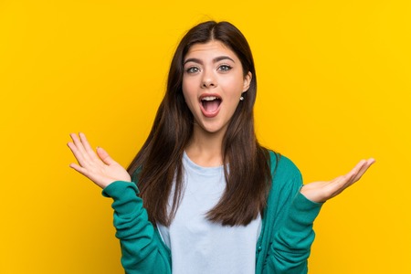 Teenager girl over yellow wall with surprise facial expressionの写真素材