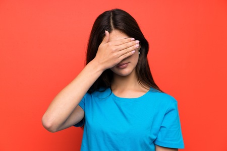 Teenager girl with blue shirt covering eyes by handsの写真素材
