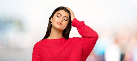 Teenager girl with red sweater with an expression of frustration and not understanding at outdoorsの写真素材