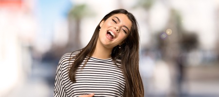Teenager girl with striped shirt smiling a lot at outdoorsの写真素材