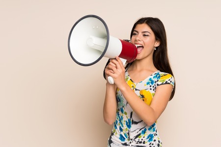 Teenager girl with floral dress shouting through a megaphoneの写真素材