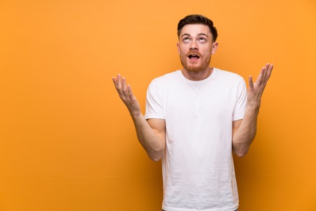 Redhead man over brown wall frustrated by a bad situationの写真素材