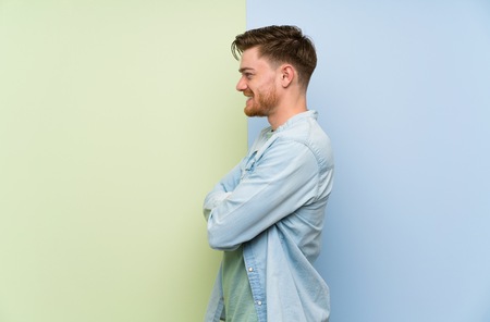 Redhead man over colorful background in lateral positionの写真素材