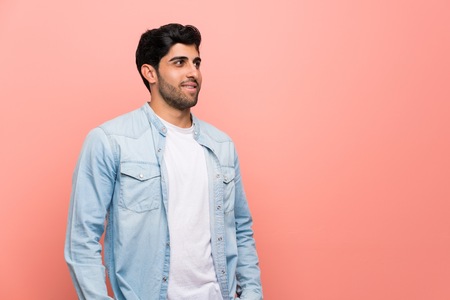 Young man over pink wall laughing
