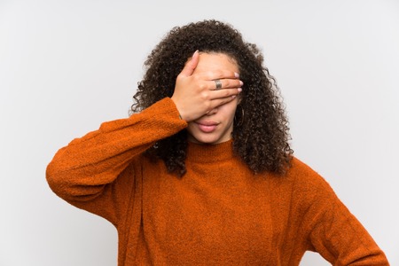 Dominican woman over isolated white wall covering eyes by handsの写真素材