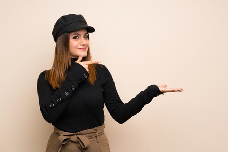 Fashion woman with hat holding copyspace imaginary on the palm to insert an adの写真素材