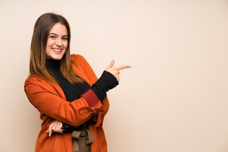 Young woman with coat pointing finger to the sideの写真素材