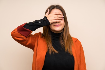 Young woman with coat covering eyes by handsの写真素材