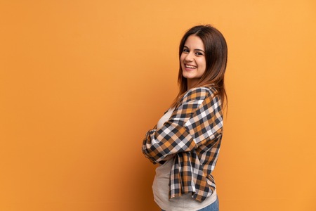 Young woman over brown wall with arms crossed and happyの写真素材