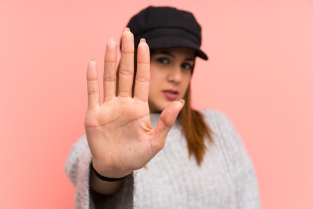 Fashion woman with hat over pink wall making stop gesture with her handの写真素材
