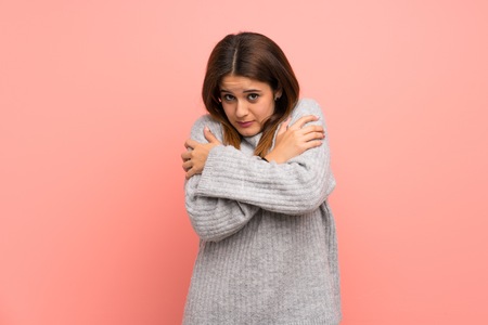 Young woman over pink wall freezingの写真素材