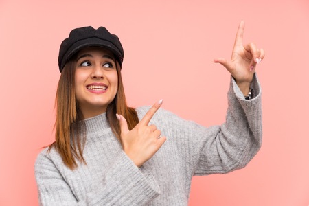 Fashion woman with hat over pink wall pointing with the index finger a great ideaの写真素材