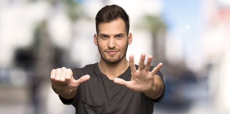 Man with black shirt counting six with fingers at outdoors