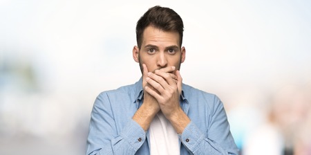 Handsome man covering mouth with hands for saying something inappropriate at outdoors