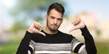 Handsome man showing thumb down at outdoorsの写真素材