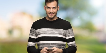 Handsome man sending a message with the mobile at outdoorsの写真素材