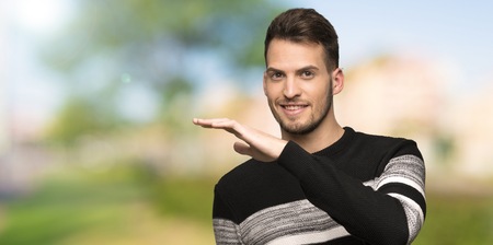 Handsome man holding copyspace to insert an ad at outdoorsの写真素材