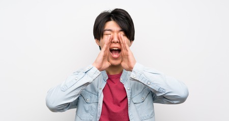 Asian man on isolated white background shouting and announcing somethingの写真素材