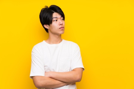 Asian man over isolated yellow wall portraitの写真素材