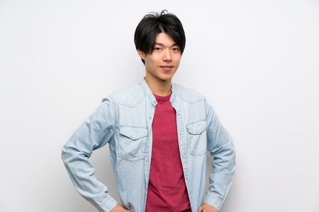 Asian man on isolated white background posing with arms at hip and smilingの写真素材