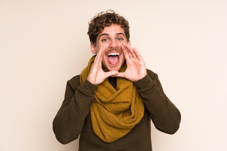 Blonde man with scarf shouting with mouth wide openの写真素材