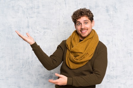 Blonde man over grunge wall extending hands to the side for inviting to comeの写真素材