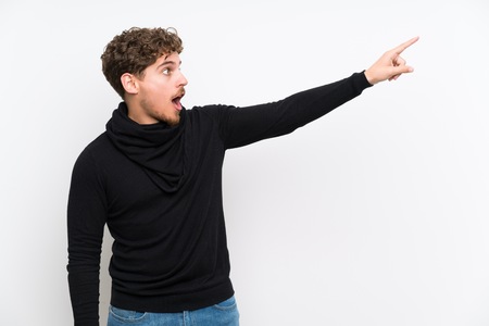 Blonde man over isolated white wall pointing awayの写真素材