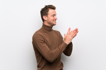 Blonde man over isolated white wall applauding after presentation in a conferenceの写真素材