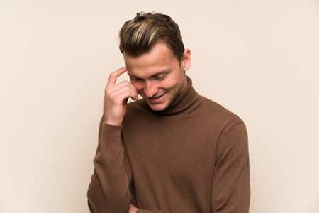 Blonde handsome man over isolated wall laughingの写真素材