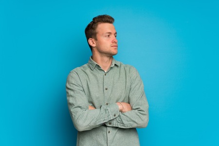 Blonde man over isolated blue wall portraitの写真素材