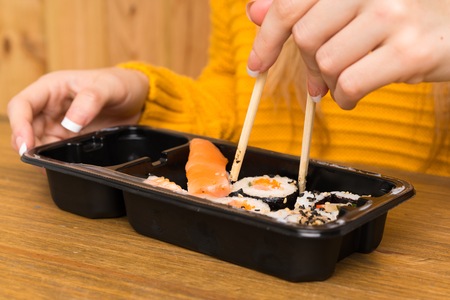 Young woman with sushi over wood background