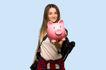 Young photographer woman holding a piggybank on isolated blue backgroundの写真素材