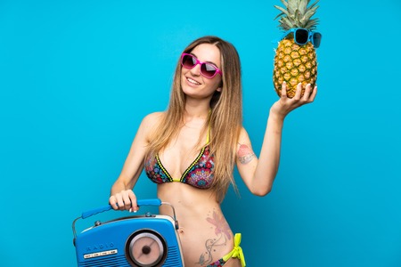 Young woman in bikini holding a radio and a pineapple with sunglassesの写真素材