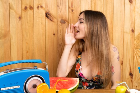Young woman in swimsuit with lots of fruits shouting with mouth wide openの写真素材