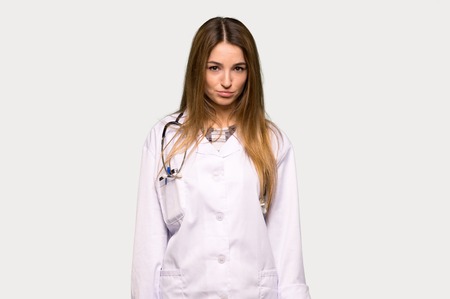 Young doctor woman with sad and depressed expression on isolated grey backgroundの写真素材