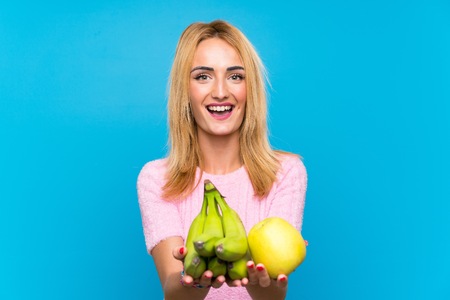 Happy Young blonde woman holding fruitsの写真素材
