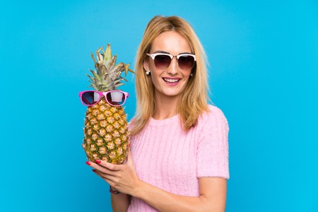 Young woman holding a  pineapple with sunglassesの写真素材