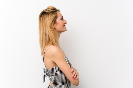 Young blonde woman over isolated white in lateral positionの写真素材