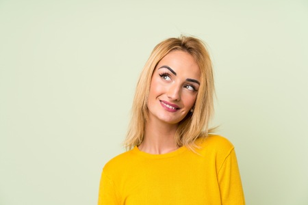 Young blonde woman over isolated green background laughing and looking upの写真素材