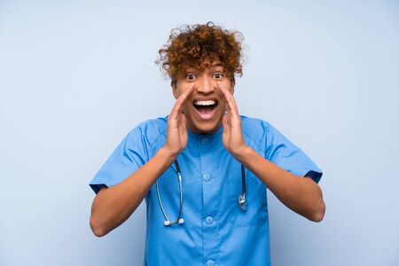 Surgeon doctor african american man shouting with mouth wide openの写真素材