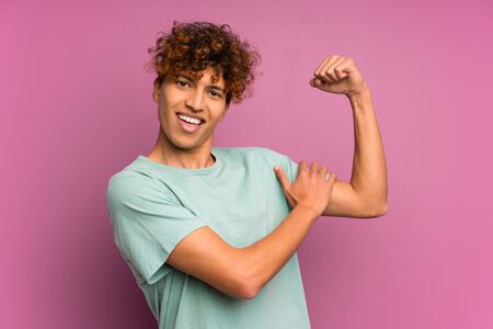 Young african american man over isolated purple wall making strong gestureの写真素材