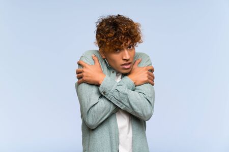 Young african american man over isolated blue wall freezingの写真素材