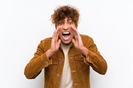 Young african american man over isolated white wall shouting with mouth wide openの写真素材