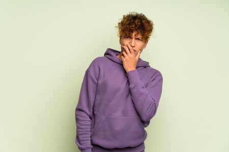 Young african american man over isolated green wall surprised and shocked while looking rightの写真素材