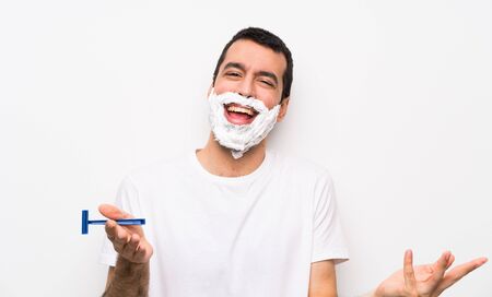Man shaving his beard over isolated white background smilingの写真素材