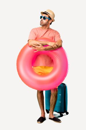 Full body of Man with hat and sunglasses on his summer vacation having doubts and with confuse face expression while bites lip. Questioning an idea on isolated backgroundの写真素材