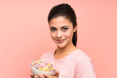 Teenager girl having breakfast cereals over isolated pink wallの写真素材
